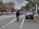 A view of Mass Ave. There are 4 general travel lanes, separated by a median. A cyclist rides in a paint-only bike lane between the general travel lane and a curbside parking lane.